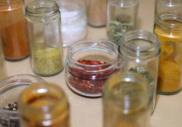 set of different spices in glass jars. paprika, pepper, turmeric, chili, dry basil and others