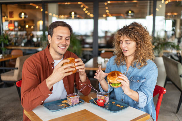 istock Young couple laughing and enjoying burgers 2196920862