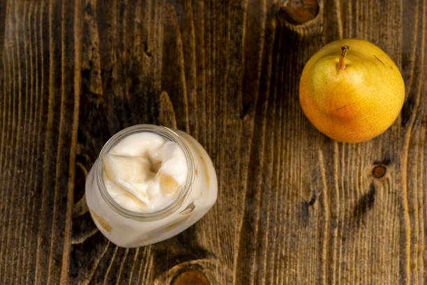 ripe pears and yogurt in a glass jar, pear yogurt with pieces of fruit, closeup