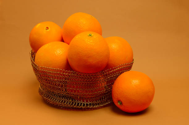 Close-up of an orange in a basket whole on an orange background