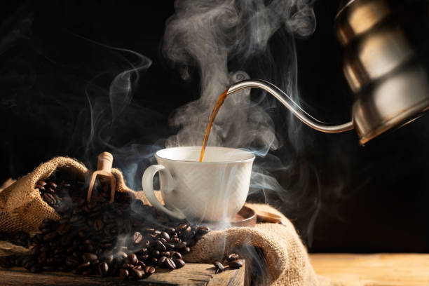 istock Pour black coffee into a coffee cup There are roasted coffee beans on the table. with a black background and dark colors 2196929405