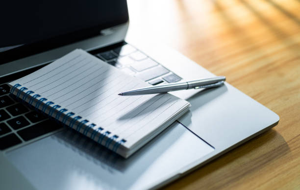 istock Laptop computer with pen and spiral notebook on desk 2196931573