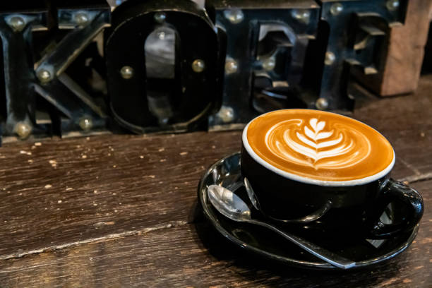 Close-up of a decorated latte with drip coffee makers on display in a cozy café.