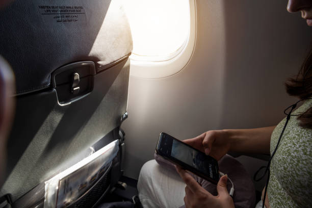 istock Young Woman Using Smartphone During Daytime Airline Flight 2196932733