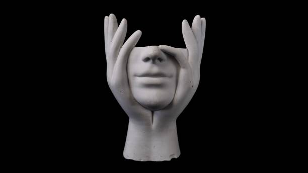 istock A white ceramic sculpture displays a face supported by hands, standing against on a solid black background, creating a serene and artistic atmosphere 2196932878