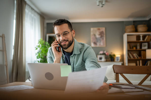 istock Businessman on a phone call, working remotely with laptop and papers 2196935929