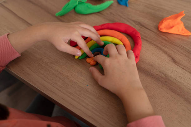 istock Little girl hands close up playing with modeling clay on table 2196936843