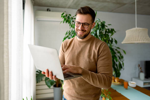 Young Man Working From Home on Laptop, Smiling and Typing