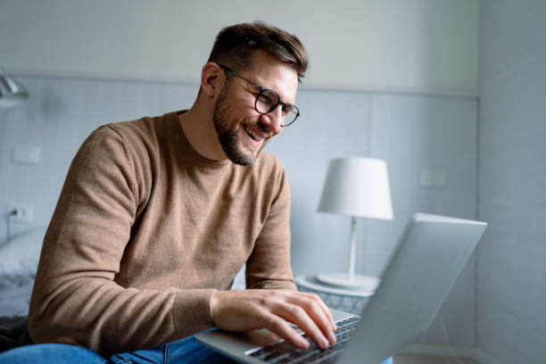 istock Young man working from home, laughing and typing on his laptop 2196937025