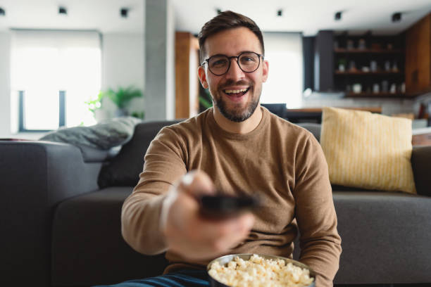 istock Man enjoying a movie night with popcorn and remote control 2196937292