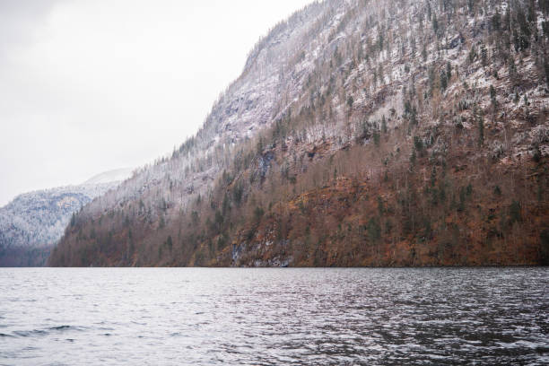 Calm waters mirror snow-covered peaks amidst a serene winter landscape.