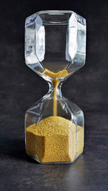 istock Close up transparent Hourglass with Falling golden Sand in dark background, Every second count, running out of time or time up or passage of time concept 2196944661
