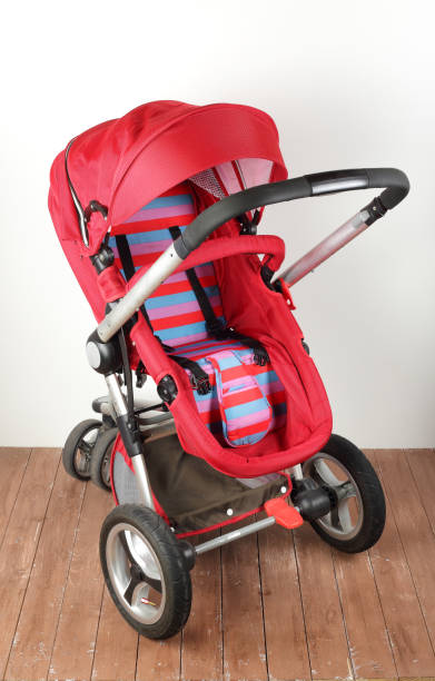 istock Red universal baby stroller on a wooden floor 2196947161
