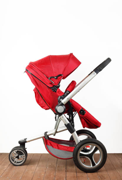 istock Red universal baby stroller on a wooden floor. Side view 2196947197