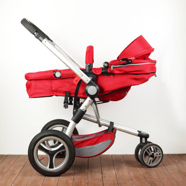 istock Side view red universal baby stroller on a wooden floor. 2196947278