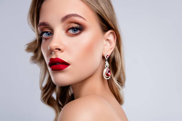 istock Attractive chic girl with red pomade ruby gem stone earrings looking in camera over grey background 2196948365