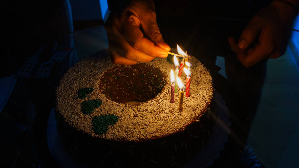 istock Man's hands lighting candles on a birthday cake 2196952090