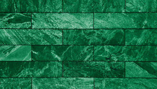 close-up view of a floor clad in rectangular green slate tiles, a smooth, uniform of marble stone surface with subtle variations in shade and texture, creating a visually appealing modern aesthetic.