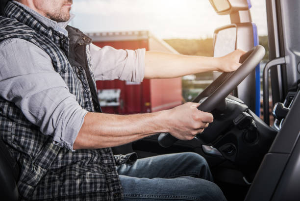 istock Semi Truck Driver Steering a Large Vehicle While Parked Near Cargo Containers at Sunset 2196954196