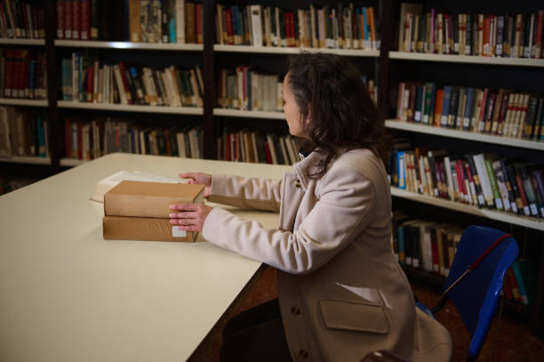 istock Woman studying in a library surrounded by books and shelves 2196955129