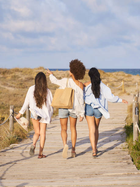 istock Young women walking on wooden boardwalk at beach 2196956739