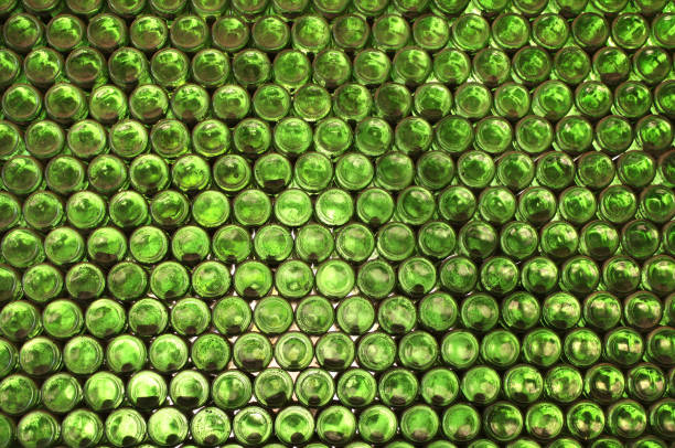 istock Full frame wall with empty green beer bottles bottoms. Alcohol theme. Endless rows of wine bottles. Green glass bottle wall with sunlight from behind 2196964390