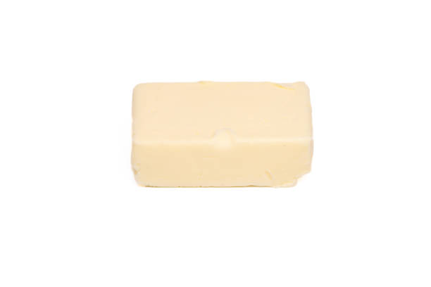 An unwrapped stick of butter reclines on its paper, faint creases and soft sheen suggesting rich texture, home baking traditions, and the first step toward sauces, pastry, or toast.