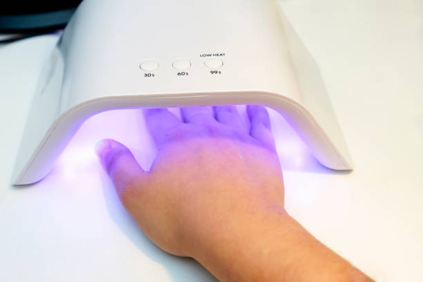 istock Hand under UV LED nail lamp curing gel polish on a white surface 2196968929