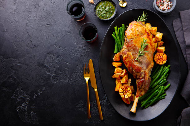 istock Roasted lamb leg with potato and green bean. Black background. Copy space. Top view. 2196969702