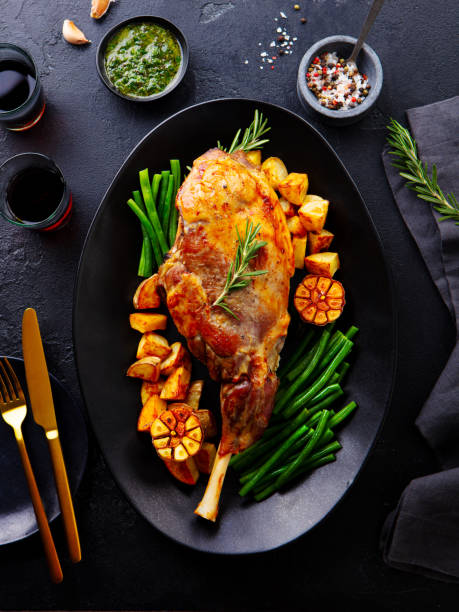 istock Roasted lamb leg with potato and green bean. Black background. Top view. 2196969708