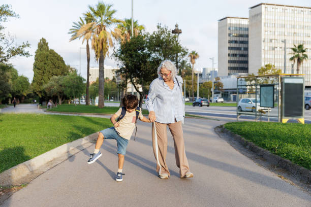 istock Grandmother holding grandson's hand while walking in city park 2196974544
