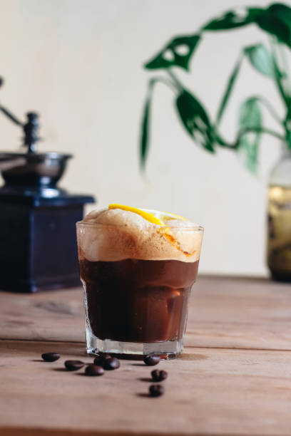 istock A freshly brewed cup of dark coffee topped with a vibrant lemon slice, resting on a rustic wooden table. 2196974823