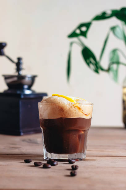 istock A freshly brewed cup of dark coffee topped with a vibrant lemon slice, resting on a rustic wooden table. 2196974844