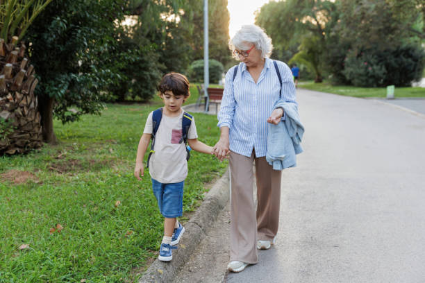 istock Grandmother holding grandson's hand while walking in park 2196974954