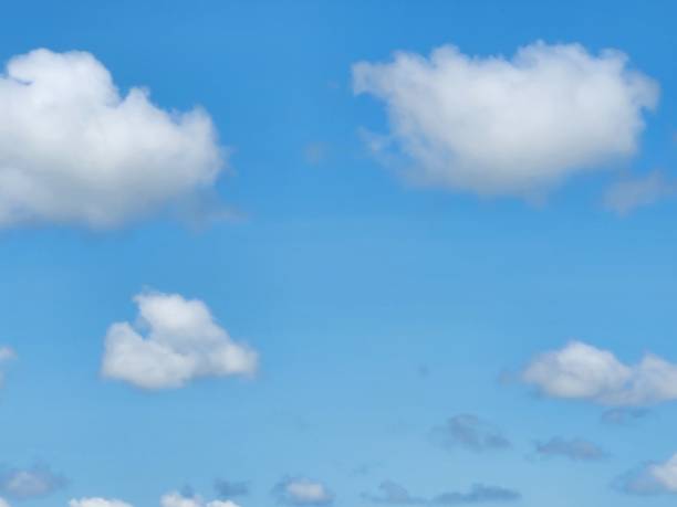 The open sky, adorned with white clouds drifting gently, creates a tranquil and serene landscape, where the sunlight blends with soft shadows, bringing a sense of peace.