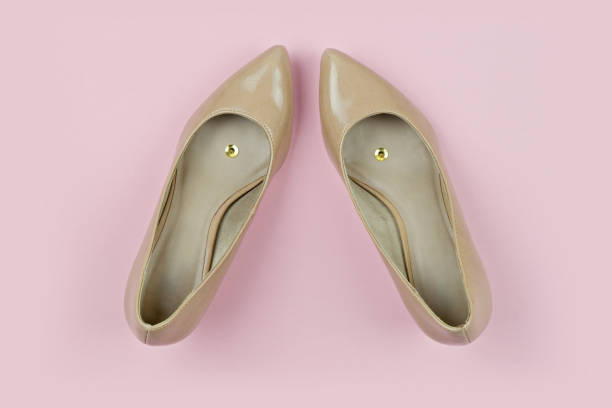 Pair of Beige Shoes With Push Pins Inside on Yellow Background With Copy Space, above view