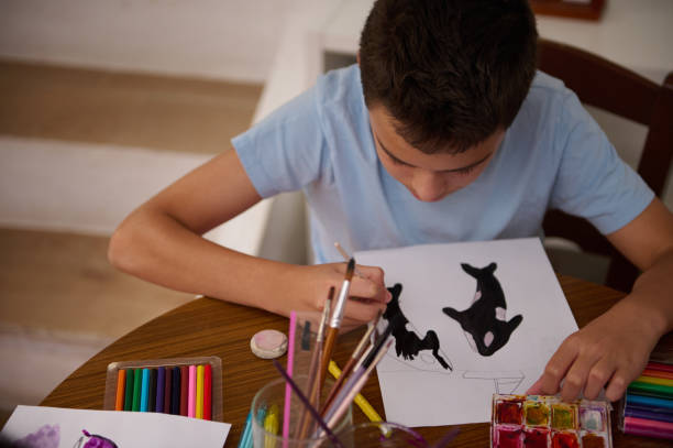 istock Young boy painting artistic designs with colors at a table 2196978106