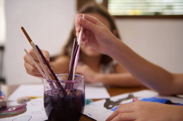 A young girl engaged in painting outdoors, showcasing her artistic talents and creativity, with visible paint on her hands and a serene background.