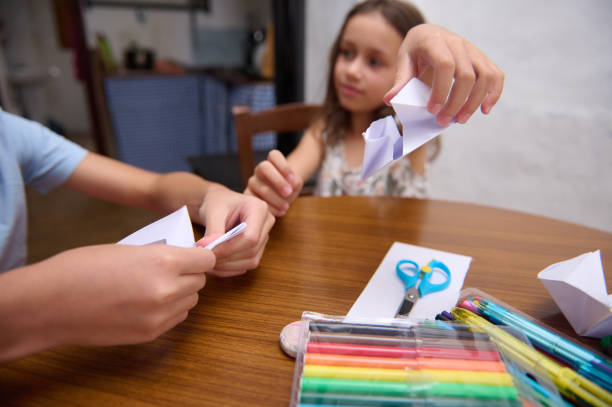 istock Children engaging in crafting activities at a table, creating paper figures. 2196978143
