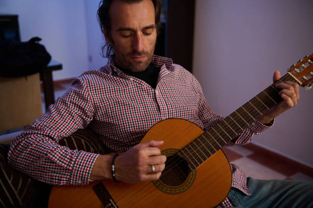 istock Man playing an acoustic guitar in a cozy indoor environment 2196978275