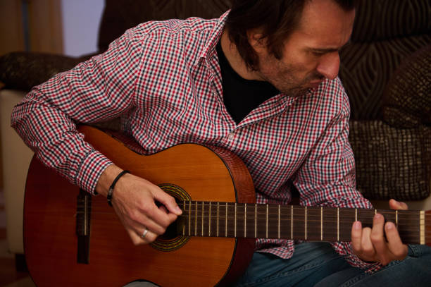 istock Man playing an acoustic guitar at home in casual setting 2196978290