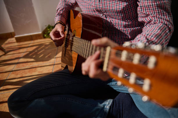 istock Musician playing an acoustic guitar under soft sunlight on a sunny day 2196978328