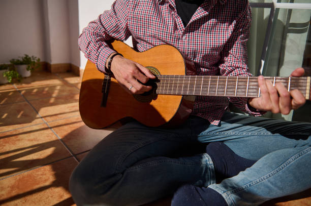 istock Man playing acoustic guitar seated on sunny terrace 2196978335
