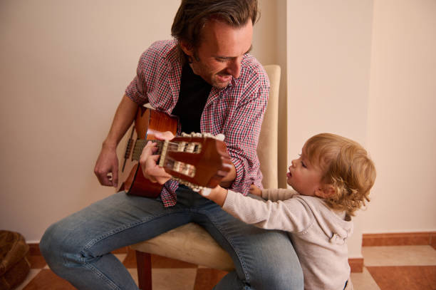istock Father bonding with his child while playing the guitar at home 2196978442