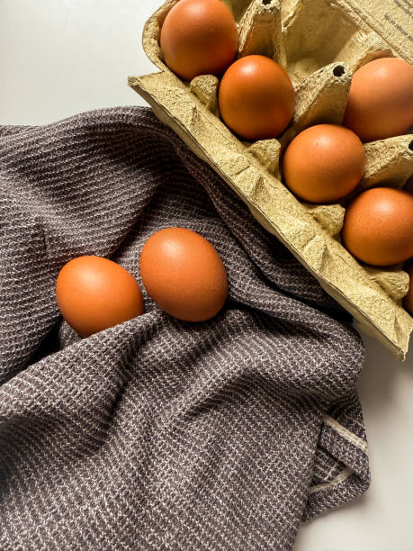 Brown chicken eggs in a paper tray and on kitchen towel