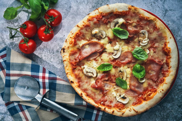 Pizza with bacon and ham and tomatoes on a wooden table,