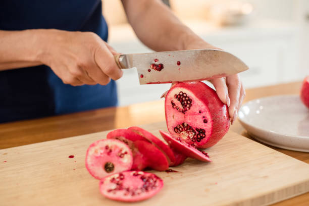 istock Woman slicing a pomegranate with a knife 2196987194