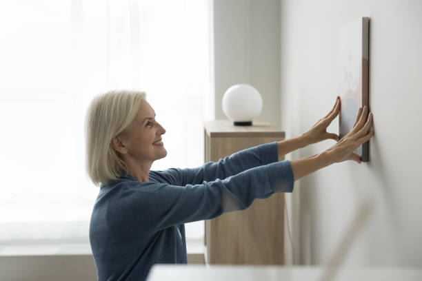 istock Caucasian woman decorating home hanging canvas on wall 2196987257