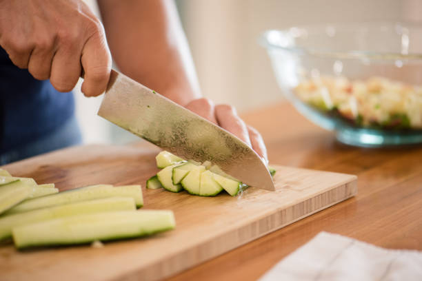 istock Woman cutting a cucumber with a knife 2196987271