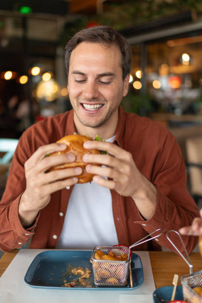 istock Young man enjoying in eating hamburger in a pub. 2196989345